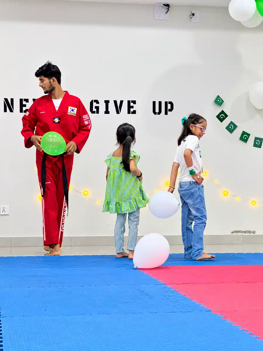 Martial arts coach guiding children at Alpha